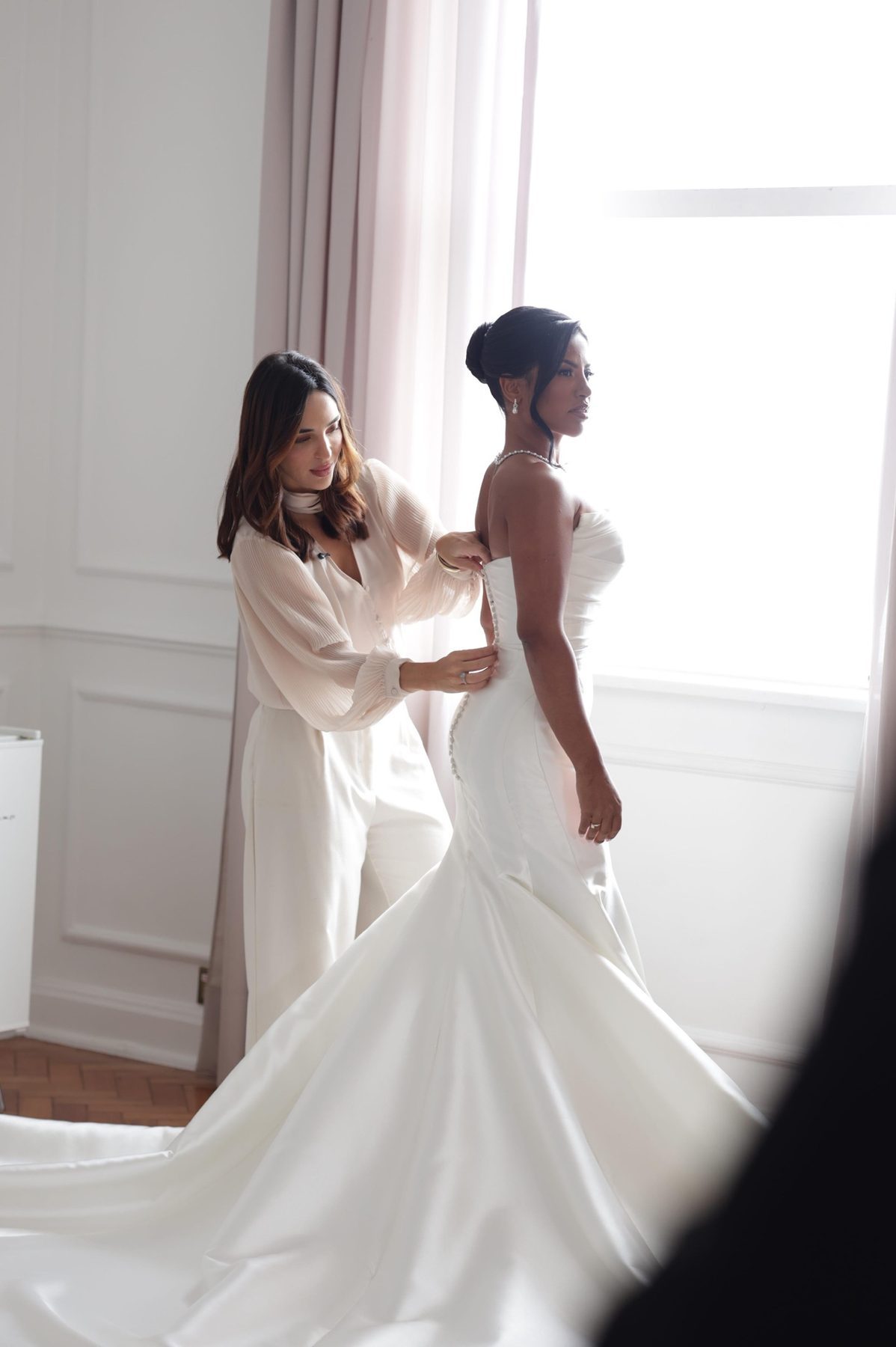 Thaís vestindo a noiva no dia do casamento